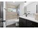 Modern bathroom with stylish tiled shower, vanity with black cabinets and gold hardware at 982 S Holly St, Denver, CO 80246