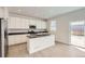 Modern kitchen with white cabinets, a center island, stainless steel appliances, and a sliding door to the backyard at 16686 E 110Th Ave, Commerce City, CO 80022