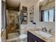Cozy bathroom featuring a granite countertop, glass shower with mosaic tile, and ample shelving at 6775 Coors Ct, Arvada, CO 80004