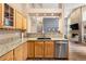 Spacious kitchen with wood cabinets, granite countertops, stainless steel dishwasher, and view into the living room at 9756 Quay Loop, Broomfield, CO 80021
