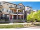 Townhome with brick and siding, featuring small, private balconies and red front doors, set in a community with green landscaping at 630 E Hinsdale Ave, Littleton, CO 80122