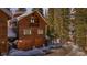 Charming two-story cabin-style home with a two car garage nestled among lush, mature trees and snow covered landscape at 960 Whispering Pines Ln, Breckenridge, CO 80424