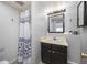 Cozy bathroom featuring a shower with black and white curtain, vanity with sink and a decorative mirror at 6282 Yank Ct, Arvada, CO 80004