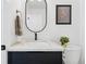 Modern bathroom with a black vanity, marble countertop, oval mirror, and white walls at 3275 19Th St, Boulder, CO 80304