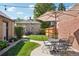 Inviting backyard with lush lawn, a patio set, mature trees, and a charming brick house at 1552 Hudson St, Denver, CO 80220