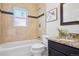 Updated bathroom features tiled walls, a shower-over-tub, granite vanity, and a large mirror at 1552 Hudson St, Denver, CO 80220
