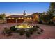 Stunning home exterior featuring a circular driveway and illuminated tiered fountain at dusk at 11541 Warrington Ct, Parker, CO 80138