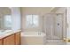 Bathroom featuring a tub, glass enclosed shower, and a window at 3906 S Quemoy Ct, Aurora, CO 80018