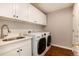 Convenient laundry room with white cabinets, sink, and modern washer and dryer at 60 Golden Eagle Rd, Greenwood Village, CO 80121