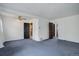 The living room features two dark paneled doorways, white walls, blue carpet, and a ceiling fan at 4850 E 18Th Ave, Denver, CO 80220