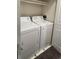 This laundry room features a white washer and dryer, next to a white door, on a tile floor at 7429 S Alkire St # 205, Littleton, CO 80127
