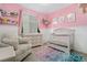 Bedroom with pink walls, white trim, a crib and an armchair at 26787 E Maple Ave, Aurora, CO 80018