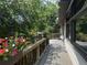 View of the deck with a wooden railing, showing the nearby trees and planter boxes of vibrant red flowers at 12173 W 27Th Dr, Lakewood, CO 80215