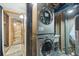 Basement laundry room featuring stackable washer and dryer, a tiled shower and exposed utility pipes at 12173 W 27Th Dr, Lakewood, CO 80215