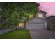 Charming two-story home with a well-manicured lawn and mature tree providing shade at sunset at 21767 Silver Meadow Ln, Parker, CO 80138