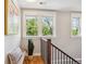 Bright hallway with hardwood floors, stairway, large windows and a quaint bench and pillow at 2683 Bellaire St, Denver, CO 80207