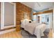 Cozy bedroom with exposed brick, wood floors, and a closet with built-in shelving at 3147 Umatilla St, Denver, CO 80211