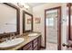 Bathroom with double sinks, granite countertops, decorative mirrors, and a glass-enclosed shower at 7804 Silverweed Way, Lone Tree, CO 80124