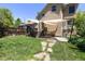 Backyard featuring green lawn, wooden fence, wooden deck, canvas shade, and exterior of tan house at 1121 S Ogden St, Denver, CO 80210