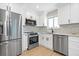 Modern kitchen with stainless steel appliances, white cabinets, and a bright window over the sink at 3657 Krameria St, Denver, CO 80207