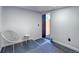 Minimalist entryway with white walls, chair, rug, and view to the outside through a modern door at 2545 S Lowell Blvd, Denver, CO 80219