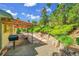 Picturesque backyard with a covered patio, stone retaining walls, mature trees and blue sky at 11267 W Colorado Pl, Denver, CO 80232