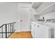 Functional laundry room on wood floors with shelving, washer and dryer, and access to stairs at 11267 W Colorado Pl, Denver, CO 80232