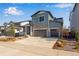 Beautiful two-story home features gray siding, stone accents, a three-car garage, and well manicured yard at 3422 N Gold Bug Ct, Aurora, CO 80019