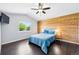 Comfortable main bedroom boasts wood accent wall, fan, plush bedding, and dark wood flooring at 3715 E 139Th Pl, Thornton, CO 80602