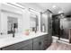Well-lit bathroom boasts a dual vanity, glass shower, and a sleek modern design at 16262 W 95Th Ln, Arvada, CO 80007