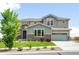 Stately two-story home featuring a manicured lawn, stone accents, and a three-car garage at 16262 W 95Th Ln, Arvada, CO 80007
