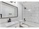 Bathroom featuring modern vanity, framed mirror, and shower with marble-patterned tile surround at 11820 Lincoln St, Northglenn, CO 80233