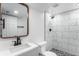Bathroom featuring modern vanity, framed mirror, and shower with marble-patterned tile surround at 11820 Lincoln St, Northglenn, CO 80233