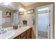 Bathroom featuring double sinks, wood cabinets, a framed mirror, and a separate shower area at 9994 Quintero St, Commerce City, CO 80022