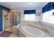Bathroom with a luxurious soaking tub, tiled surround, and separate glass-enclosed shower at 9994 Quintero St, Commerce City, CO 80022