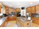 Well-lit kitchen with stainless steel appliances, light wood cabinets, and an island with a granite countertop at 9994 Quintero St, Commerce City, CO 80022