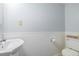 A compact bathroom with pedestal sink, toilet, wainscoting, and a vintage 'Hello Sweet Cheeks' sign at 11455 W 17Th Pl, Lakewood, CO 80215