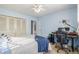 Well-lit bedroom with a ceiling fan, a bed with a blue blanket, and a desk with a black chair at 11455 W 17Th Pl, Lakewood, CO 80215