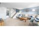 Bright living room showcasing plush carpet, a large sectional sofa, and stairs at 11455 W 17Th Pl, Lakewood, CO 80215