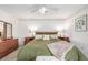 Comfortable bedroom with warm wood furniture, plush green bedding, bench, and carpeted floors at 11455 W 17Th Pl, Lakewood, CO 80215