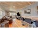 Open-concept living room with wood ceiling and floors, and a large sectional sofa at 4642 Plettner Ln, Evergreen, CO 80439