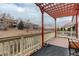A backyard deck with a pergola and railing, overlooking the greenery of the surrounding neighborhood at 16159 W 70Th Pl, Arvada, CO 80007