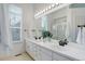 Bright bathroom featuring double sinks, a large mirror, and a separate shower area at 16159 W 70Th Pl, Arvada, CO 80007