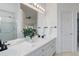 Bright bathroom with dual sink vanity, framed mirror, and glass enclosed shower at 16159 W 70Th Pl, Arvada, CO 80007