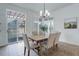 Bright dining area with a wood table, modern chandelier, and access to an outdoor deck at 16159 W 70Th Pl, Arvada, CO 80007