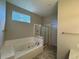 Bathroom with a tiled tub, shower with glass doors, and a bright window at 9806 Hooker Ct, Westminster, CO 80031