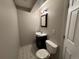 Small half bath with toilet, dark vanity, mirror, and light floral tile floor at 9806 Hooker Ct, Westminster, CO 80031