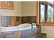 Elegant bathroom featuring a tub with stone surround, and a bright window with backyard views at 1140 Indian Peak Rd, Golden, CO 80403