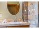 Bathroom vanity area with a round mirror and decorative tile shower with glass doors at 1140 Indian Peak Rd, Golden, CO 80403
