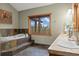 Bathroom features a large window overlooking trees, double sinks, soaking tub with stone surround at 1140 Indian Peak Rd, Golden, CO 80403